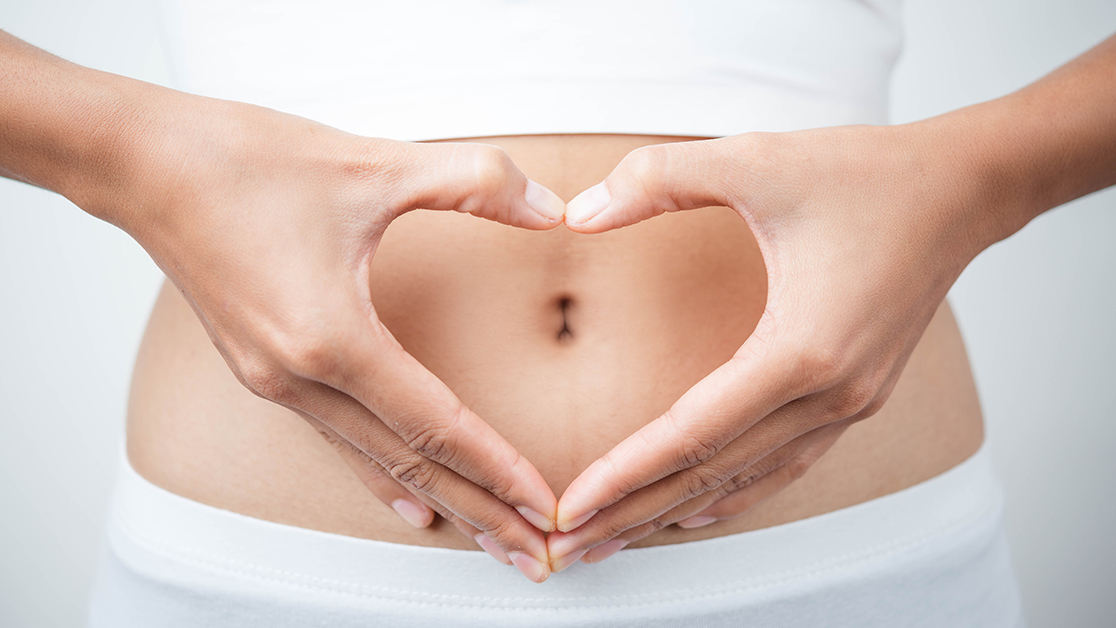 Close up of woman's hands made heart on belly